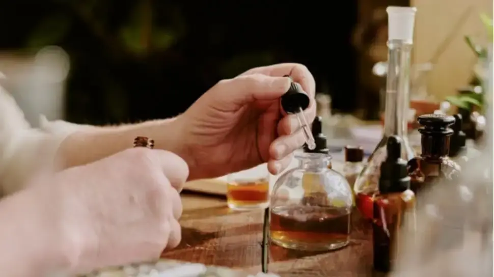 Hands of a perfumer carefully blending oils.